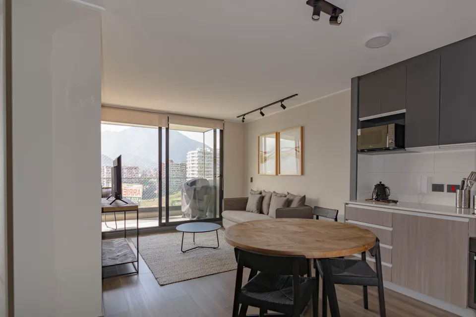 Salon lumineux ouvert sur une cuisine et un balcon
